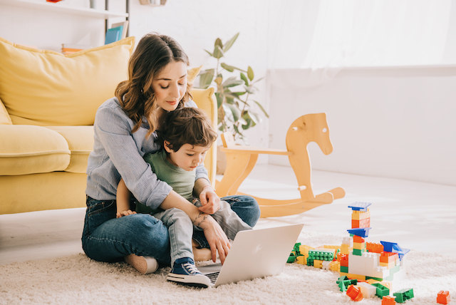 article mom and son sitting on carpet and using laptop G9PQM8S 1